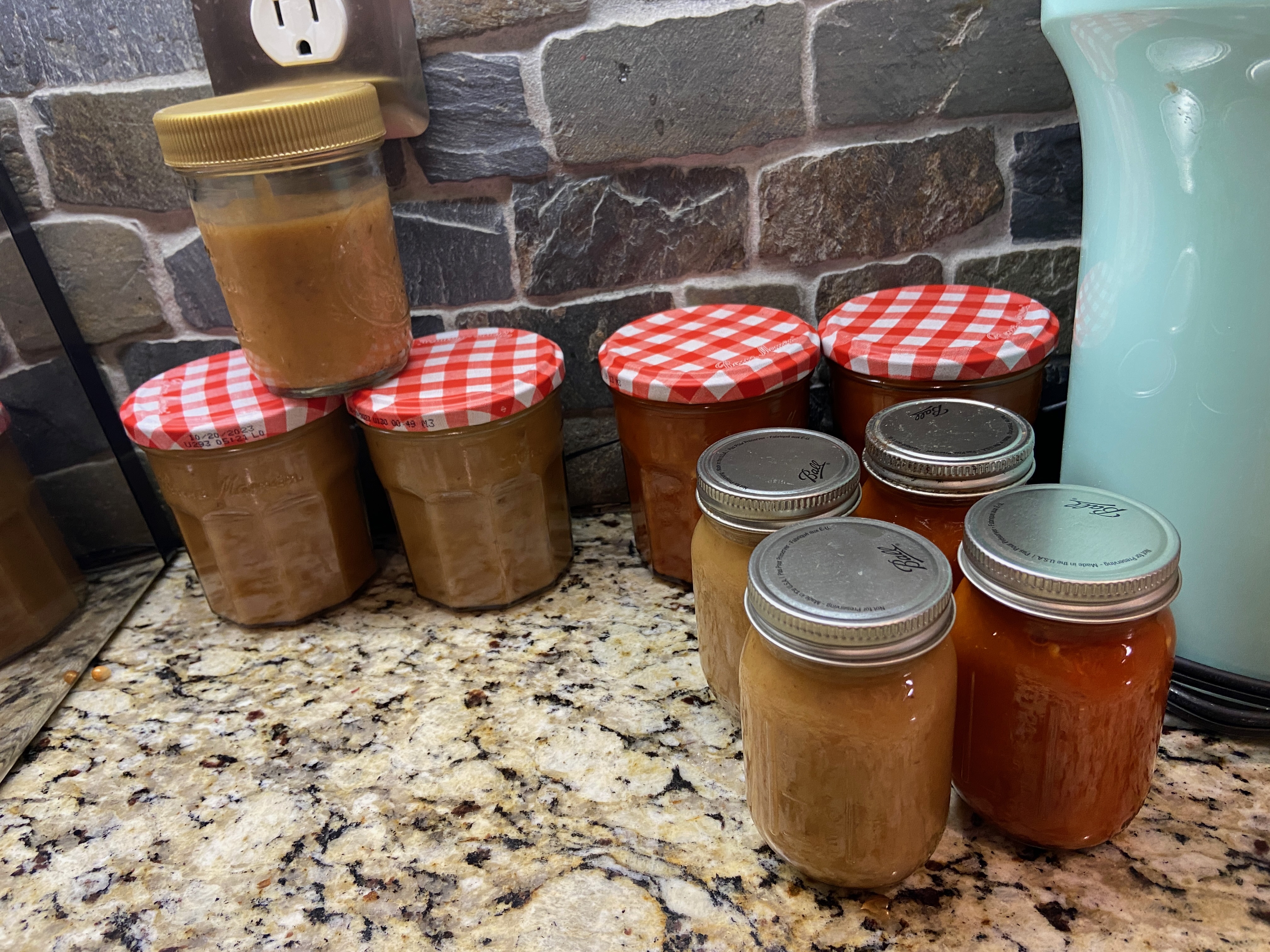 nine small jars of red and orange hot sauces